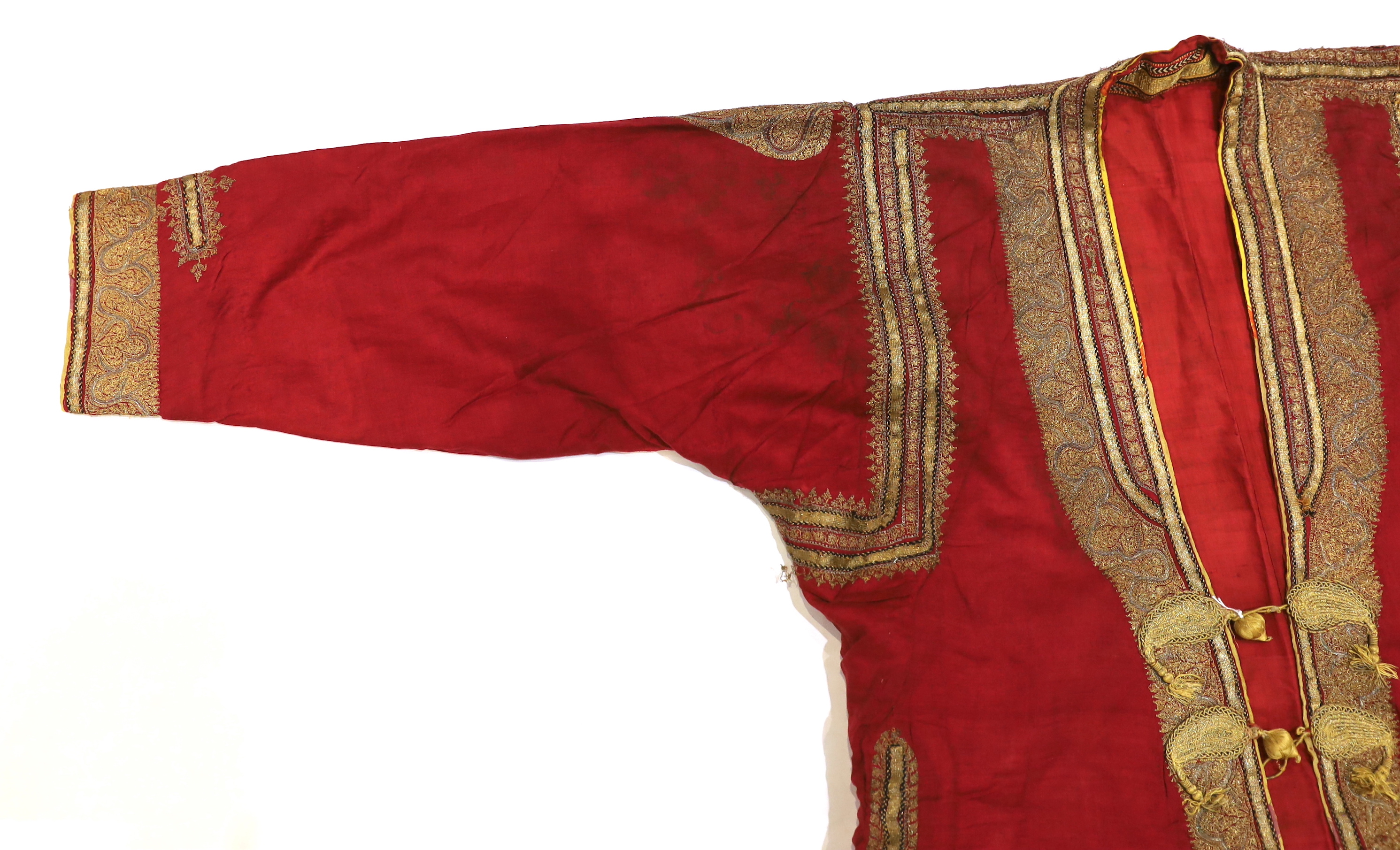 A late 19th century gentleman’s quilted red silk Indian Chogha, embroidered with ornate gold and silver metallic thread borders and paisley design details